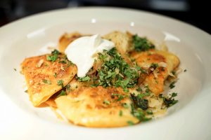 A plate of potato pierogi with sauerkraut and caramelized onions.