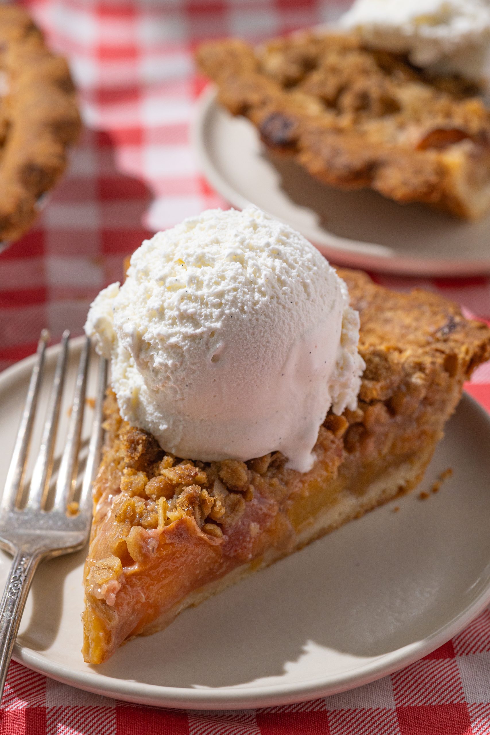 A slice of peach pie with a scoop of vanilla ice cream on top