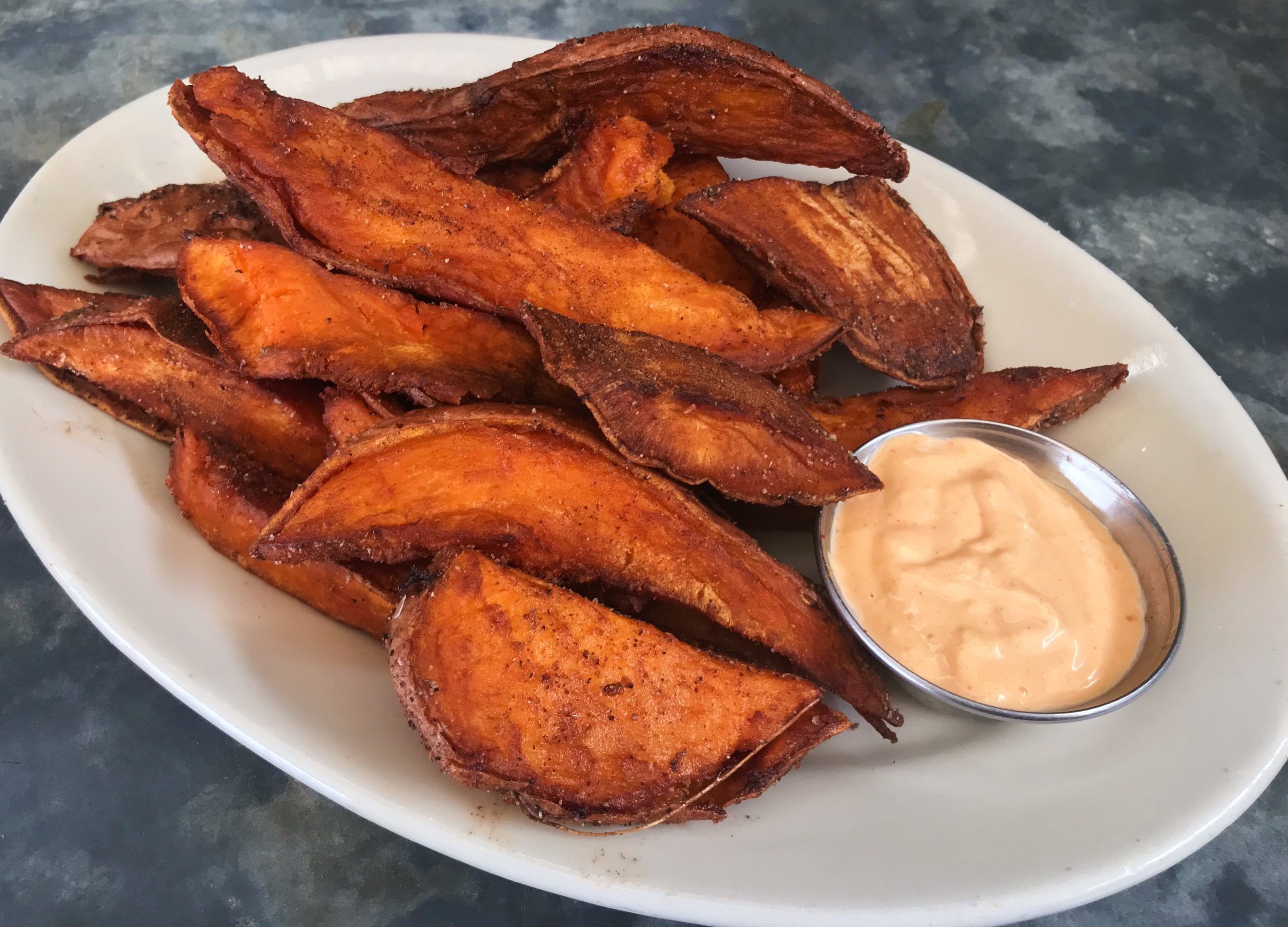A plate of sweet potatoes with curry spice and spicy mayo