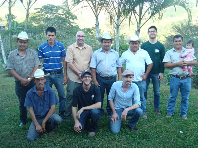 A group of Honduran coffee farmers pose, smiling.