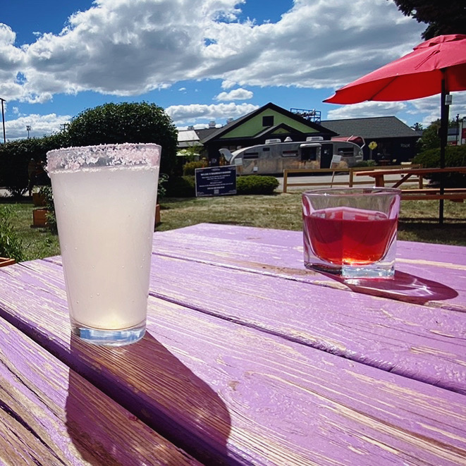 A margarita and a strawberry daiquiri on a colorful picnic table by the Roadhouse.