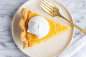 A slice of lemon chess pie, topped with a dollop of whipped cream
