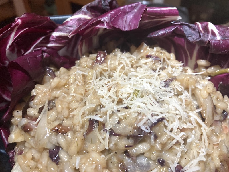 A creamy risotto with dark purple radicchio and a garnish of parmesan cheese.