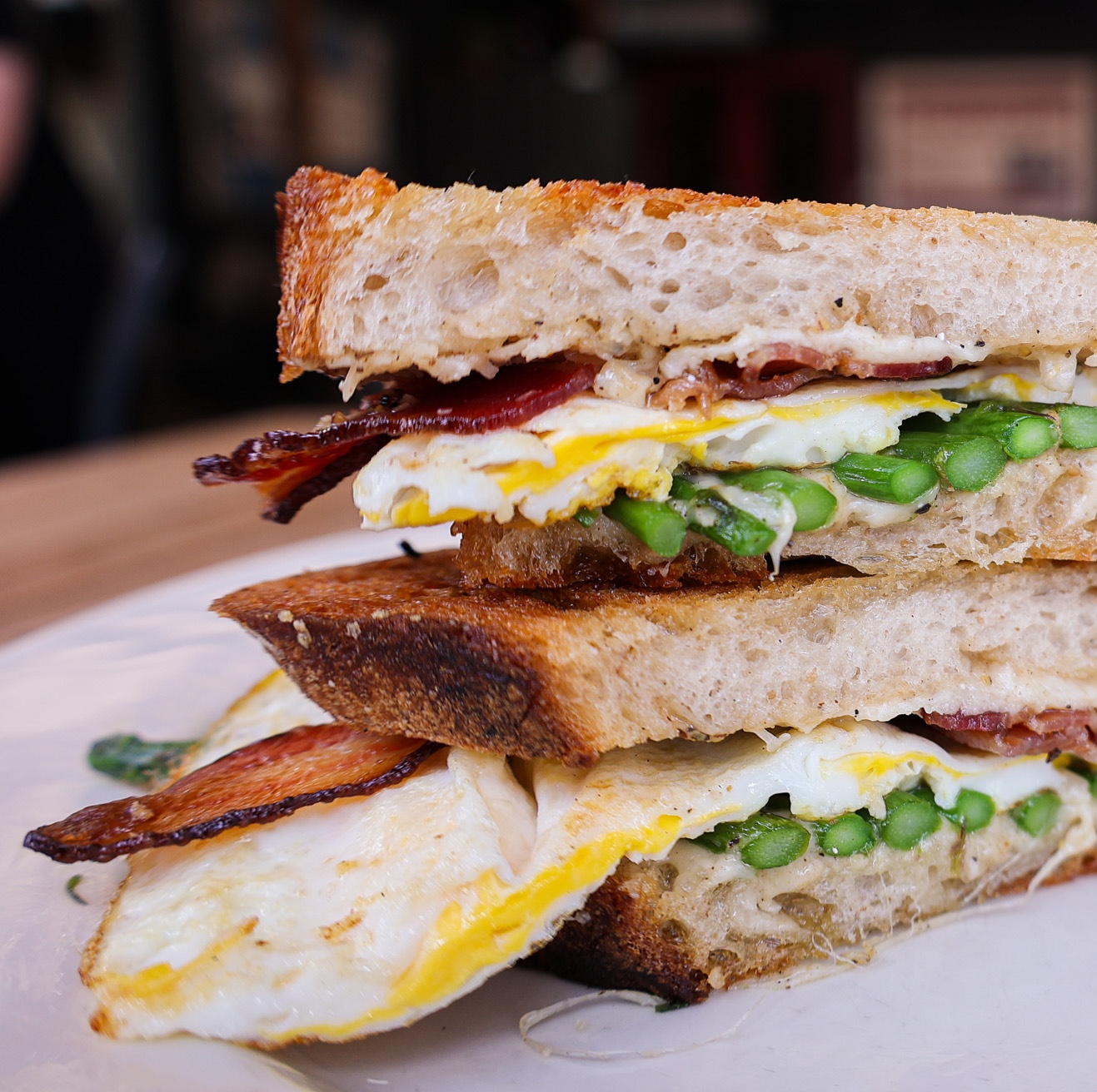 A sandwich cut open to reveal asparagus, egg, and bacon.