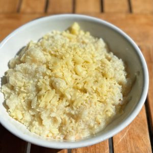 A bowl of heirloom grits topped with shredded white cheddar cheese