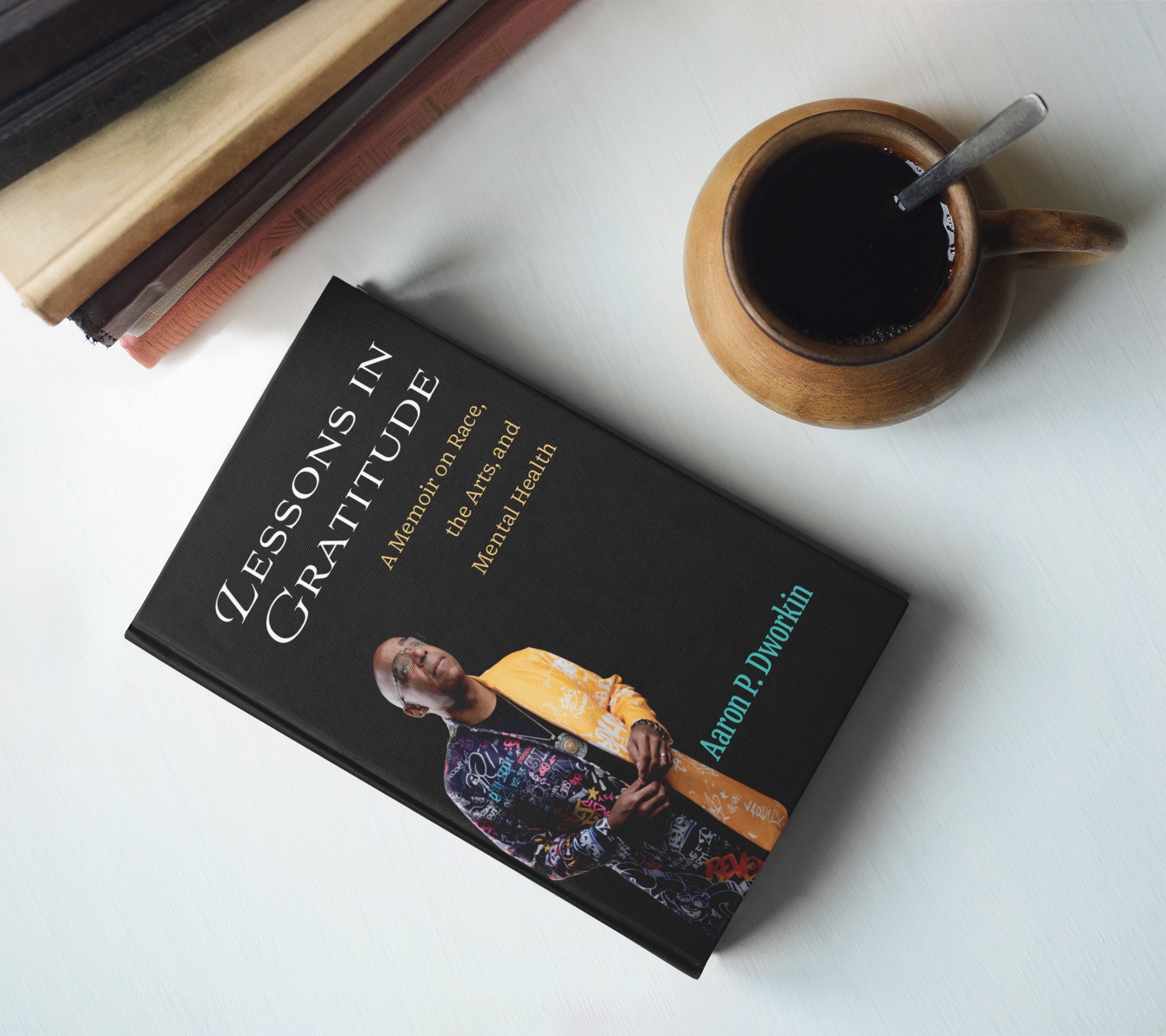 A memoir called Lessons in Gratitude by Aaron Dworkin sits on a table next to a cup of black coffee