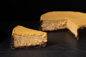 A pumpkin cheesecake with a slice removed.