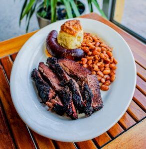 A platter full of Texas brisket, hot links, and BBQ beans.