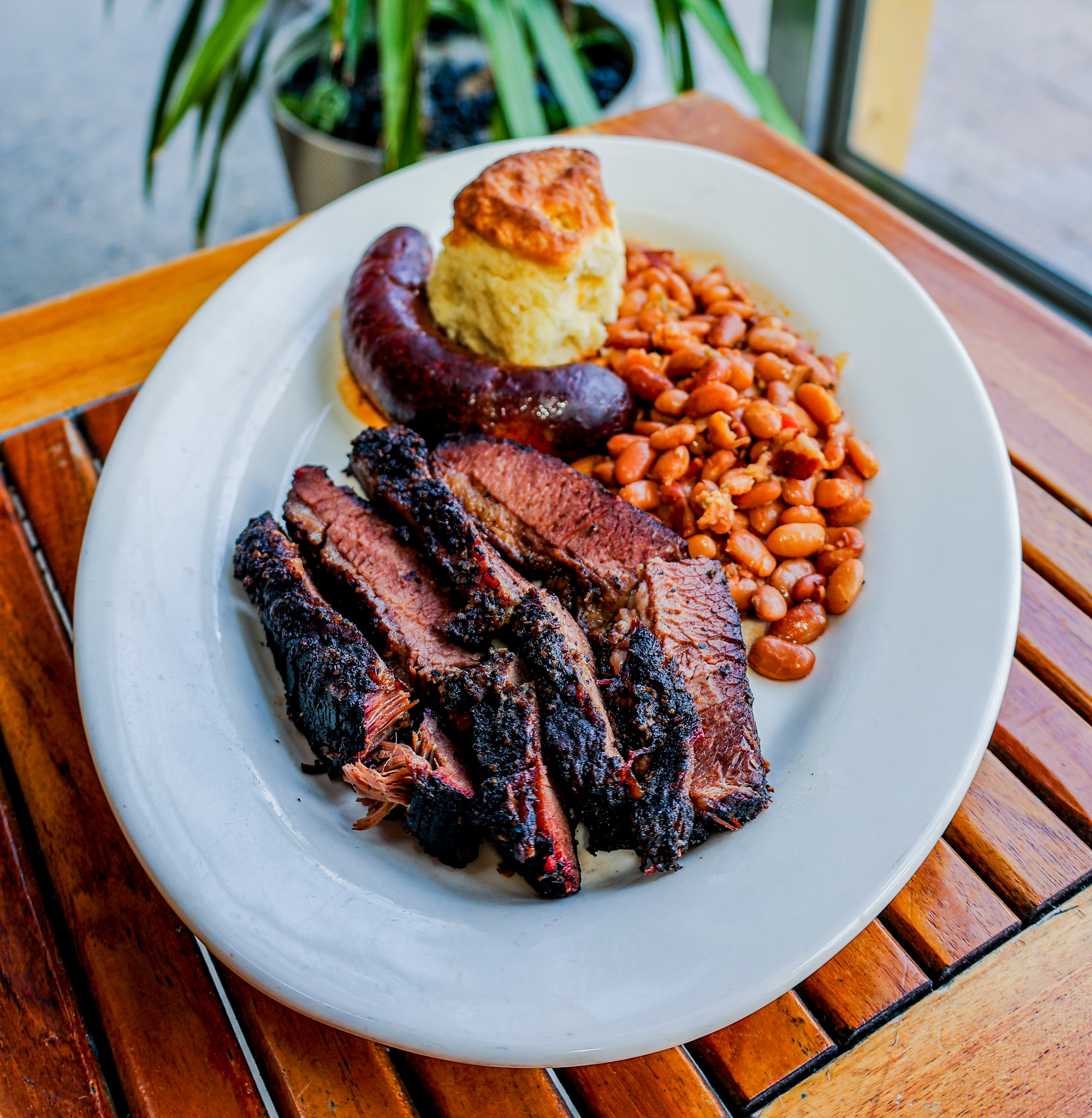 A platter full of Texas brisket, hot links, and BBQ beans.